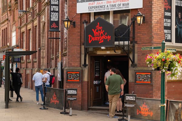L’entrée du York Dungeon, avec une pancarte, un panier de fleurs et des personnes aux alentours.