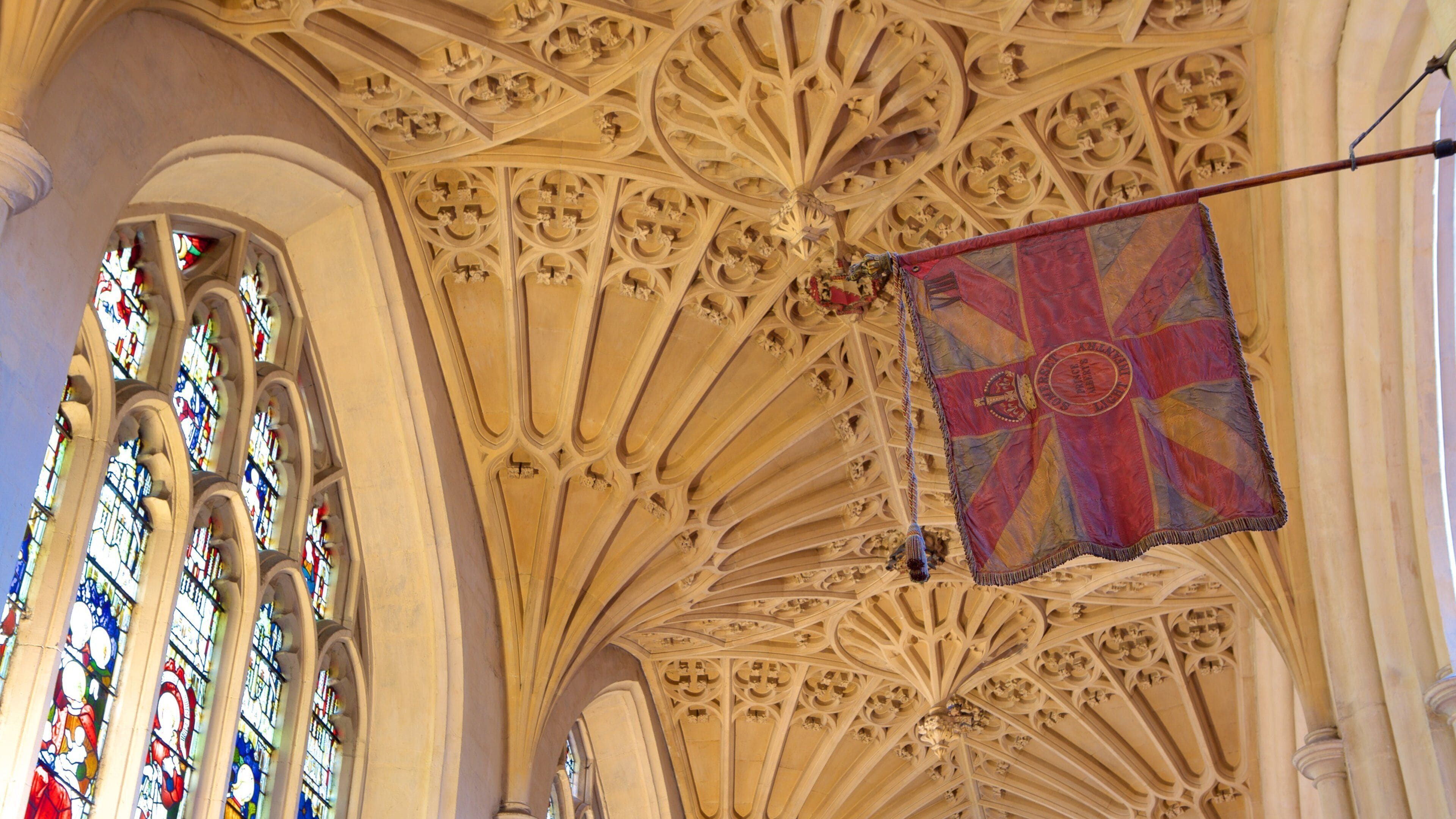 Un plafond richement décoré dans une cathédrale, orné de sculptures complexes et de vitraux.