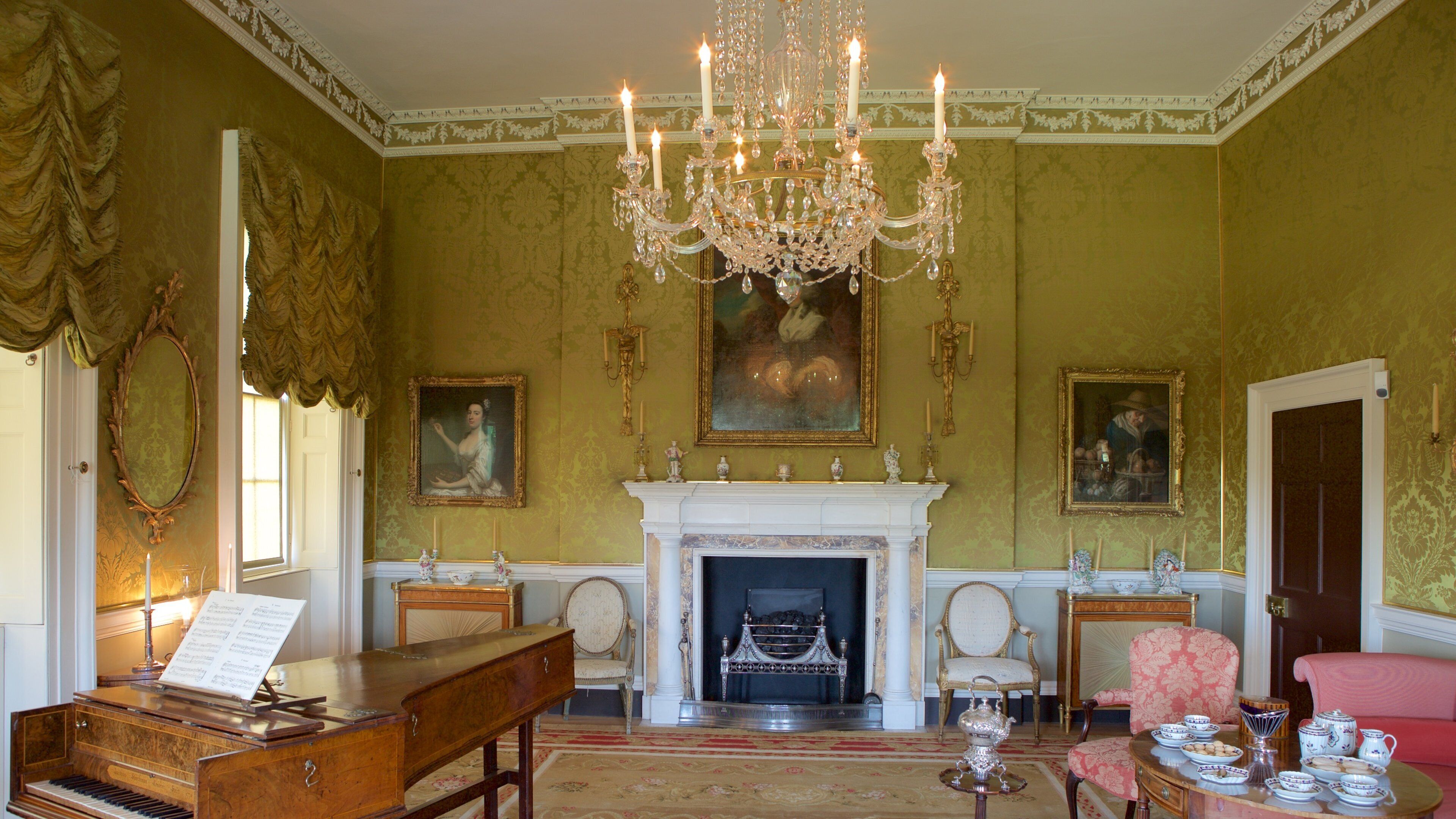 A grand room with a piano, a chandelier, a fireplace, and ornate furniture.