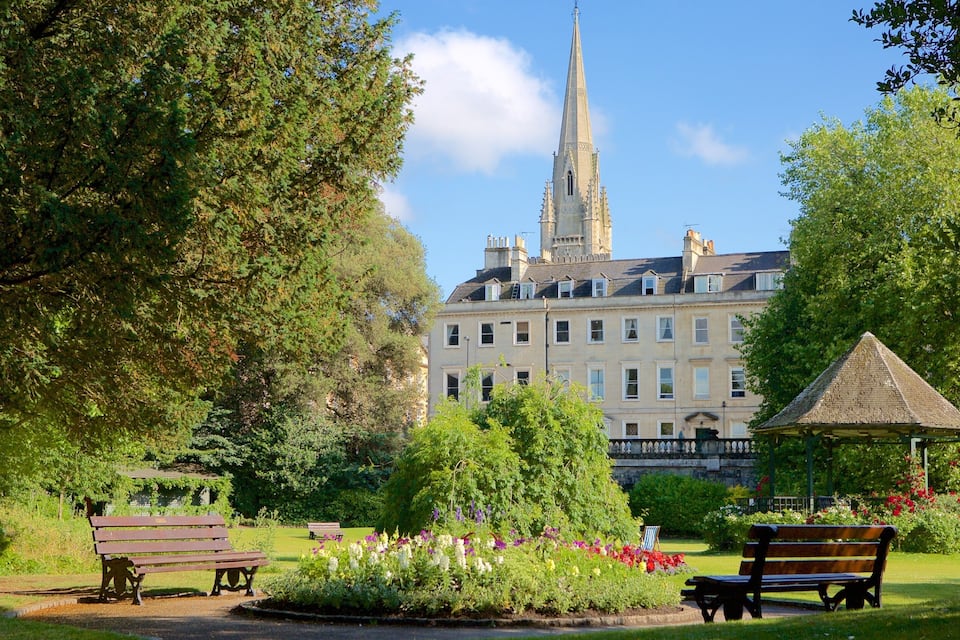 A park with benches, a gazebo, and a large building with a spire.