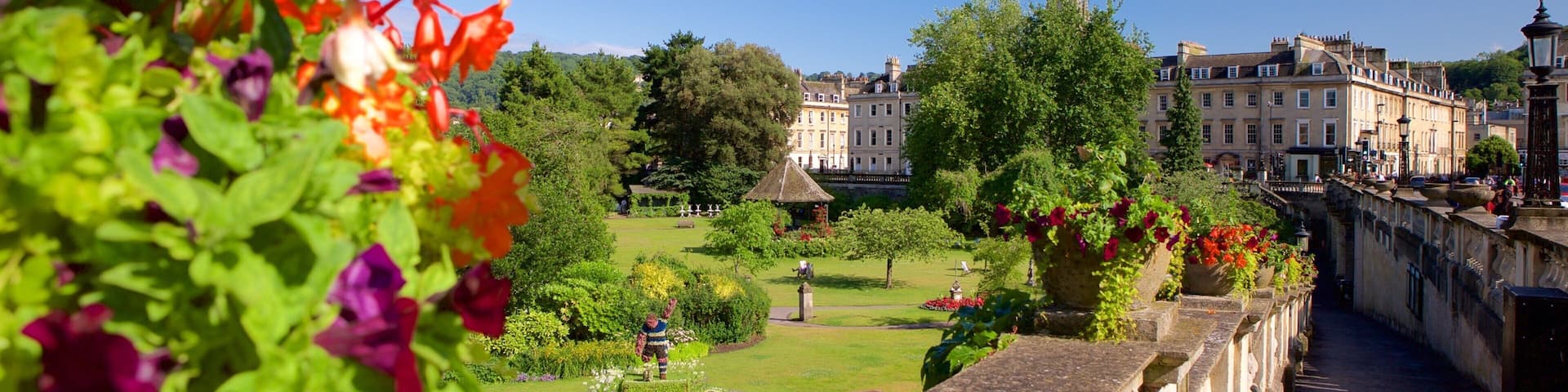 A garden with a fountain, a church spire, and historic buildings in the background.