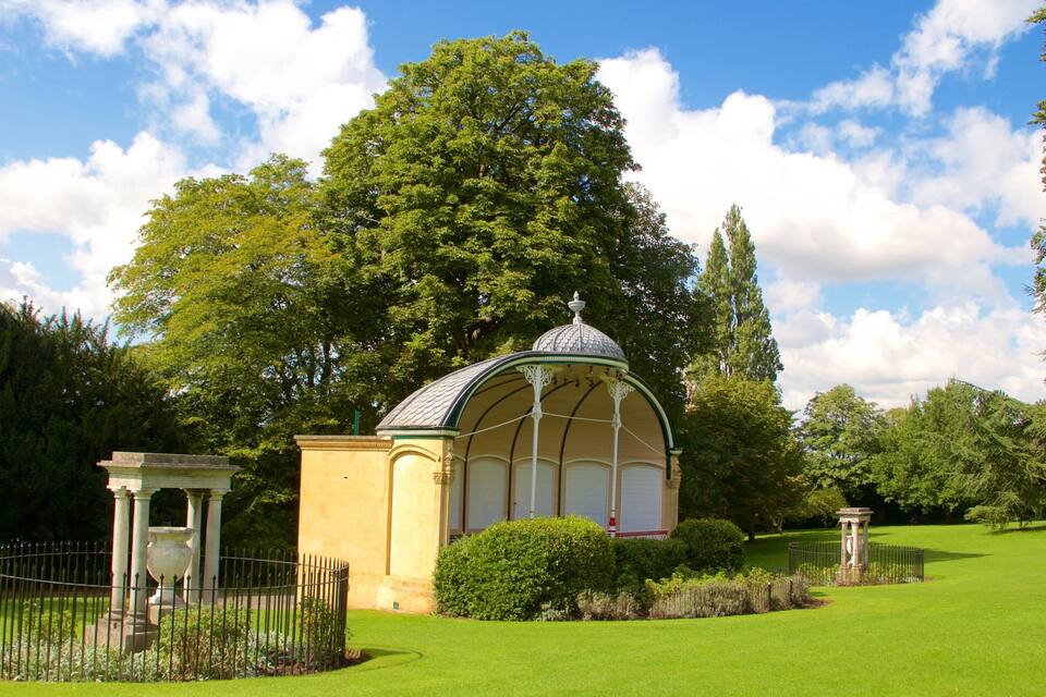 A gazebo with a dome roof surrounded by a well-manicured lawn and trees.