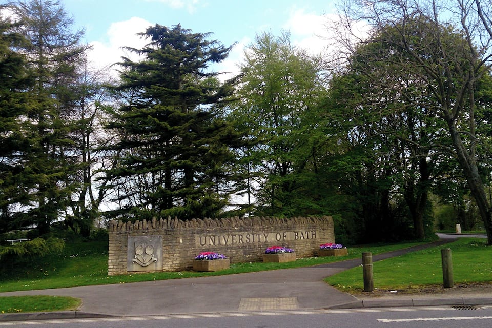 En stenvæg med inskriften "University of Bath" og to blomsterkasser.