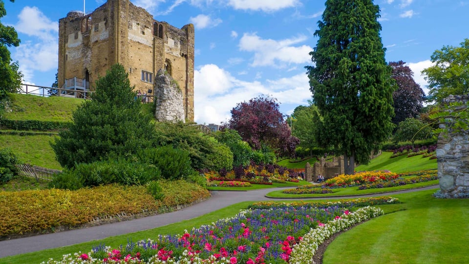 A historic castle surrounded by well-maintained gardens and a clear blue sky.