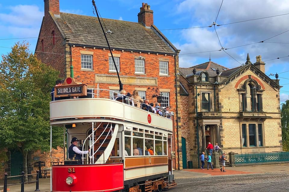 A vintage tram at Squires Gate, a historic tram station in a town with cobblestone streets and traditional brick buildings.