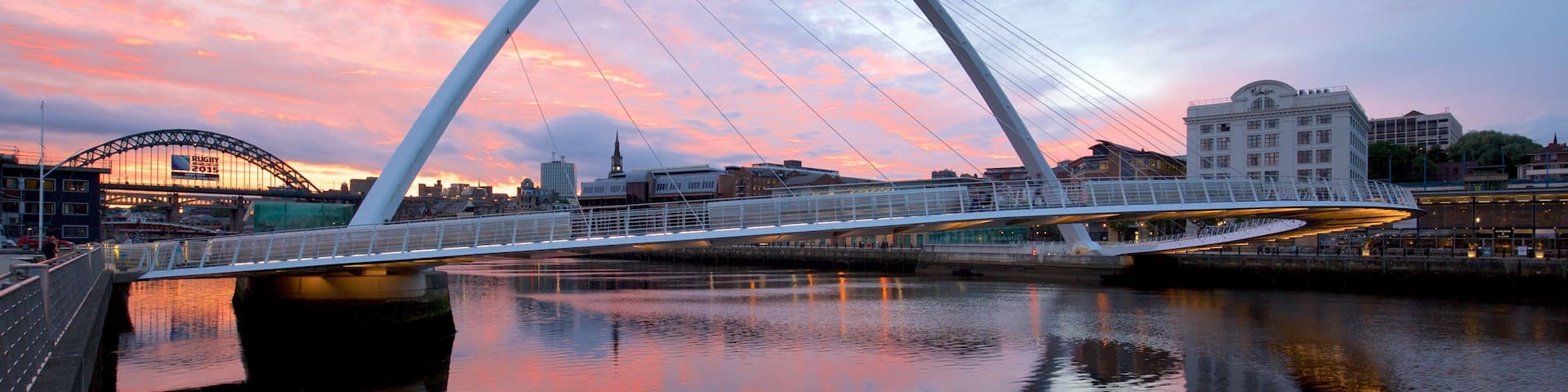 Gateshead Millennium Bridge showing a city, a sunset and a river or creek