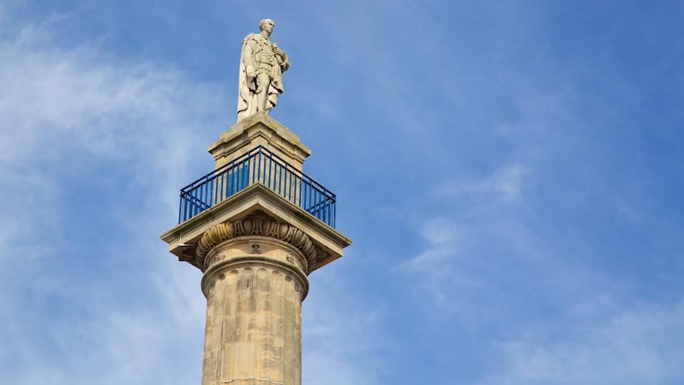 A tall stone column with a statue on top and a blue railing.