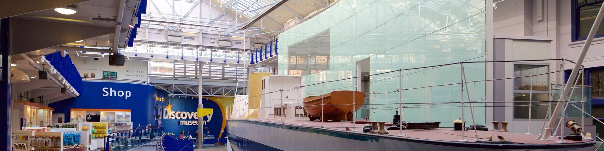 A museum with a large ship on display, a shop, and a glass wall.