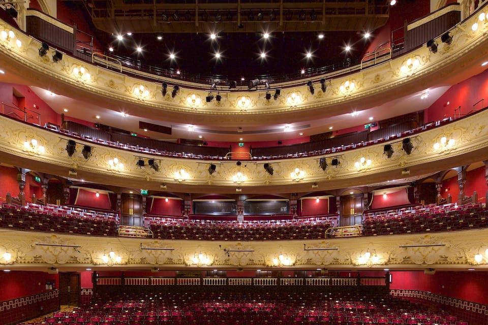 A grand, multi-tiered theater with ornate golden detailing and red seating.