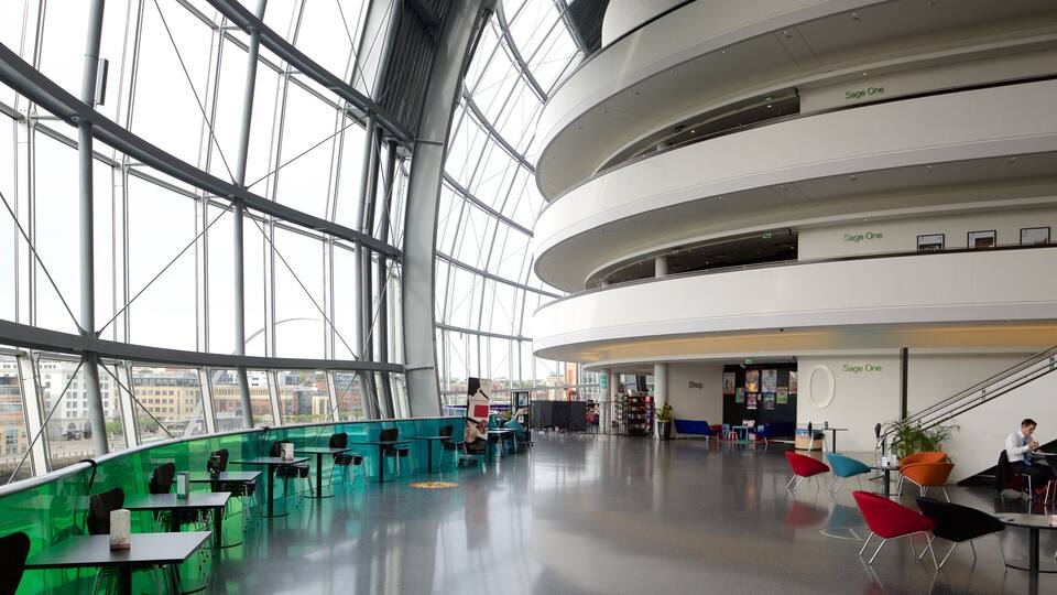 A modern indoor space with large windows, green seating areas, and a staircase.