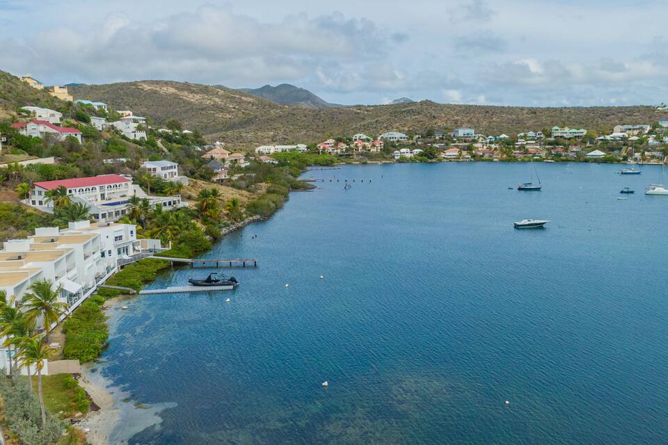 Un pueblo costero con casas, un puerto deportivo y barcos en el agua.