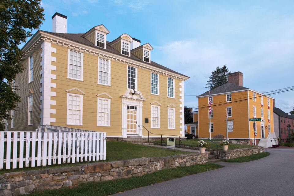 A yellow building with white trim and a white picket fence.