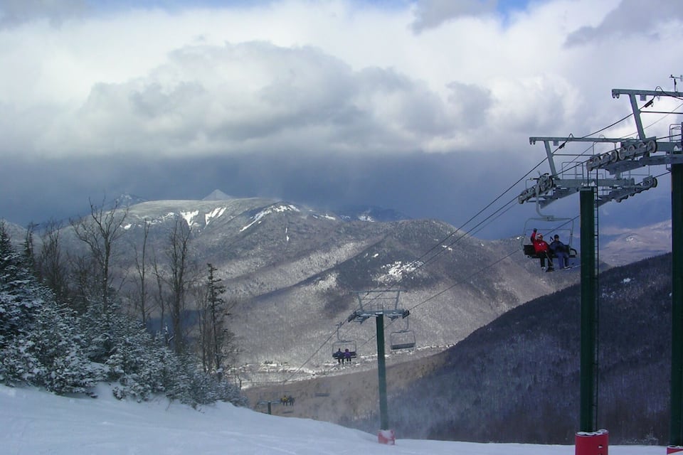 A snowy mountain landscape with a ski lift and a person on the lift.
