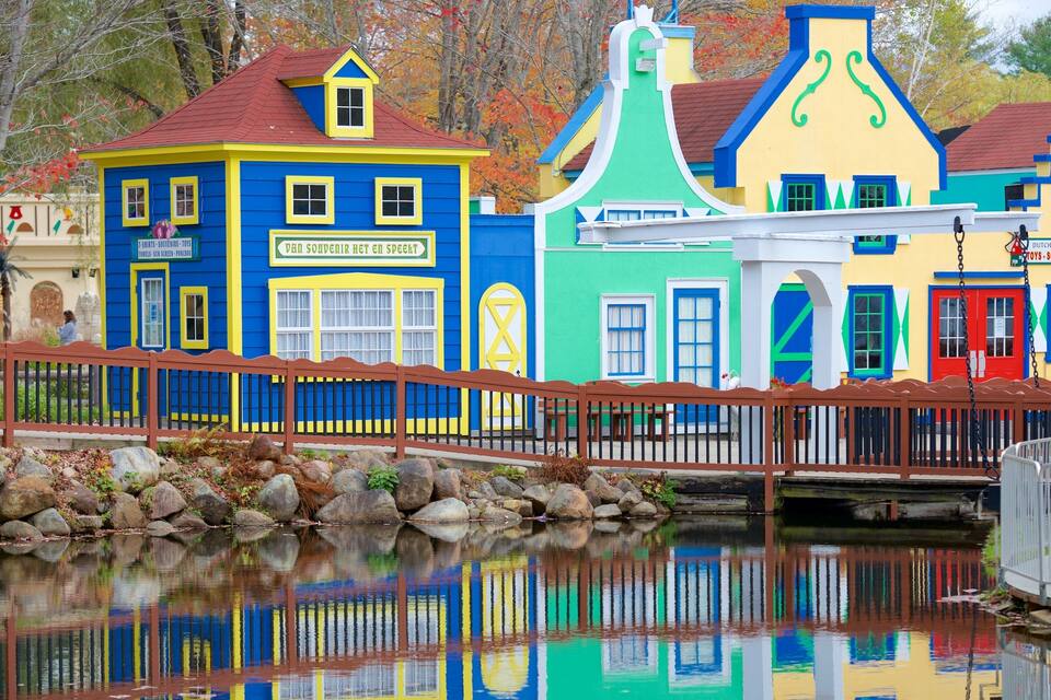 Colorful buildings with a wooden fence and a calm body of water reflecting the structures.