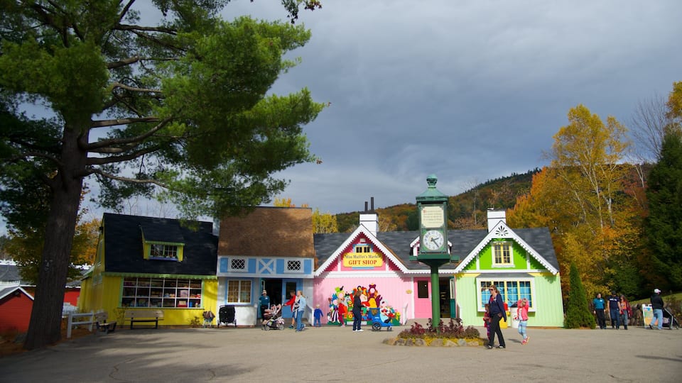 A colorful gift shop with a clock, surrounded by autumn trees and a bench.