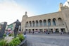A large building with arched windows and a statue in front.