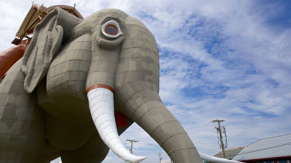 A large elephant statue with a red trunk and tusks, set against a cloudy sky.