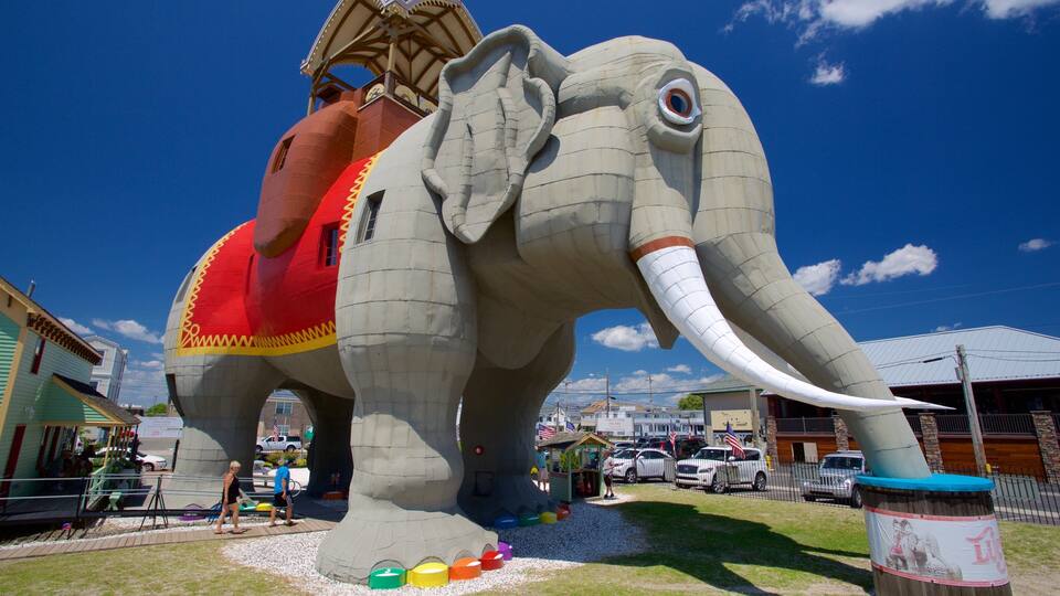 A large elephant statue with a rider, surrounded by colorful objects and parked cars.