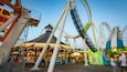 Un carnaval avec une grande roue, des montagnes russes et diverses attractions.