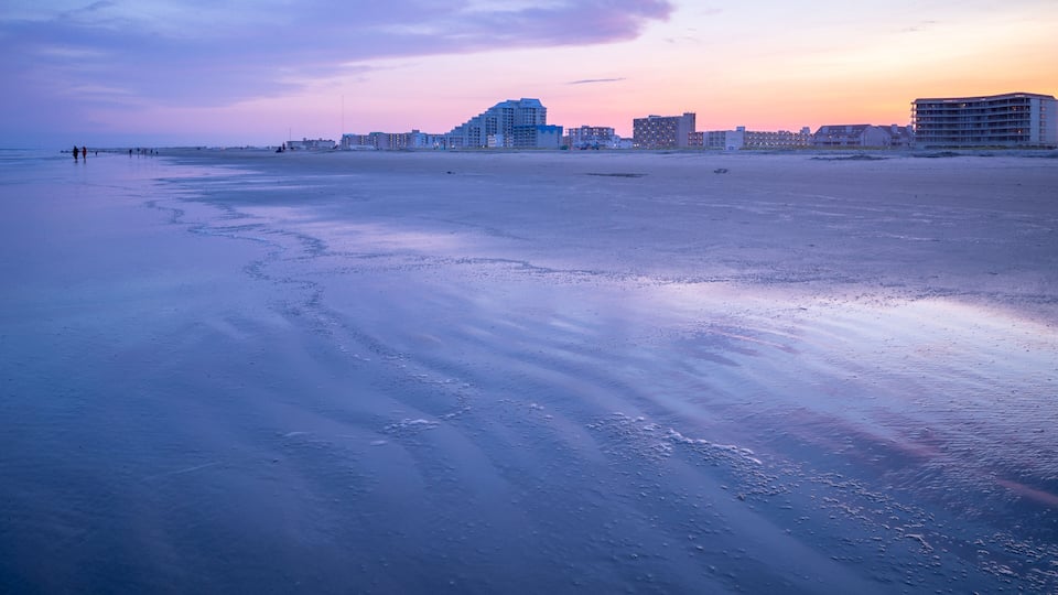 A beach with footprints and buildings in the background.
