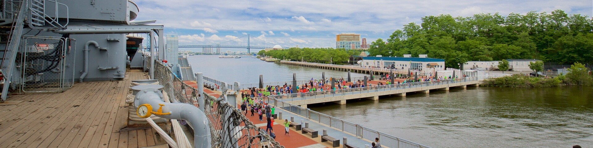 Battleship New Jersey featuring military items and a marina as well as a small group of people