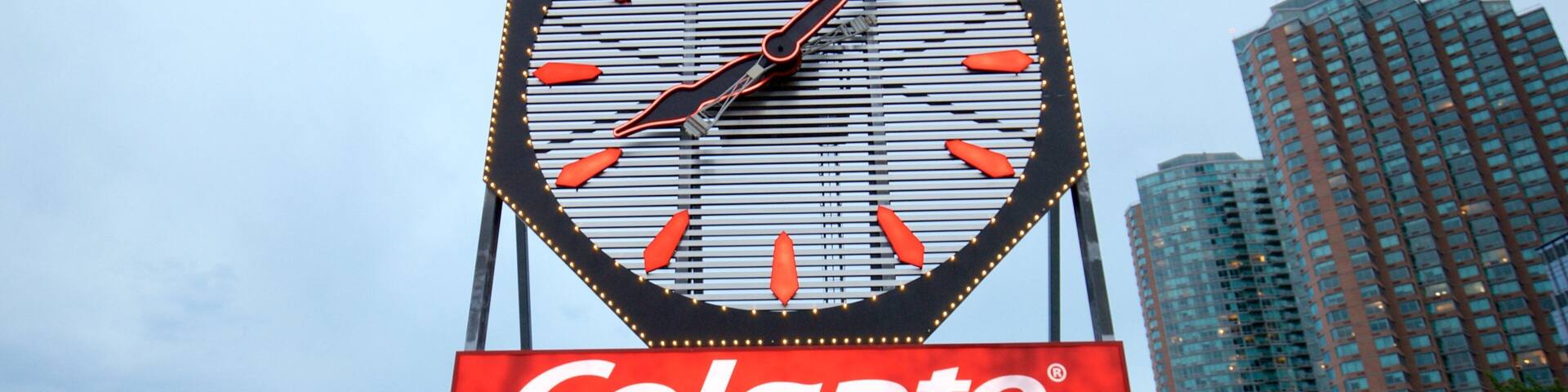 Colgate Clock which includes signage and a city as well as a small group of people