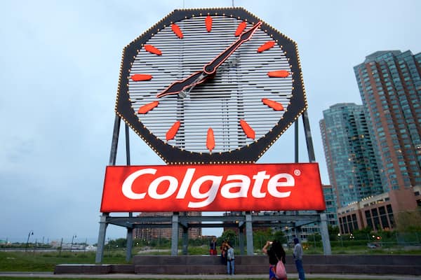 Colgate Clock featuring signage and a city as well as a small group of people