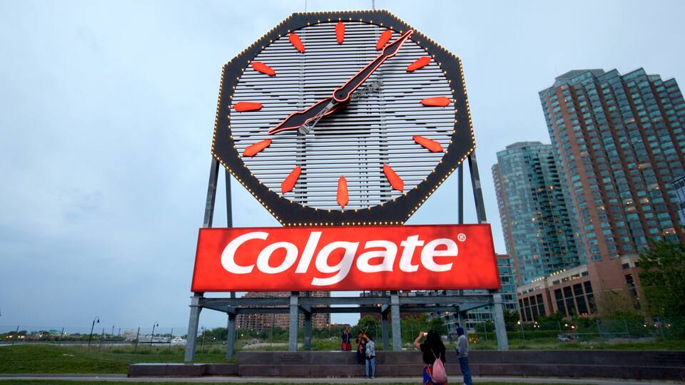 A large clock with a Colgate advertisement below it.