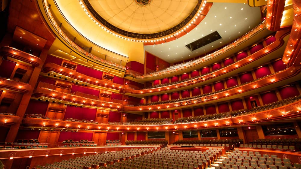 Un vaste auditorium à plusieurs niveaux, doté de sièges rouges et d’une scène circulaire.