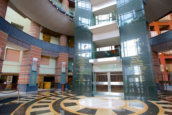 Ein modernes Gebäude mit einem zentralen Atrium, Glasgeländern und einem kreisförmigen Grundriss.