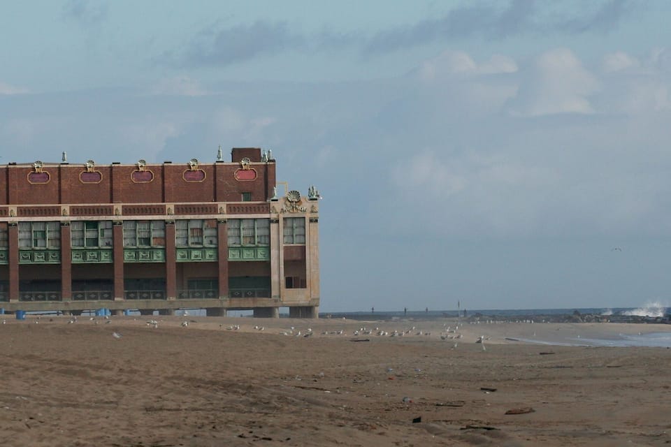 Une plage avec un grand bâtiment et des vagues qui déferlent sur le rivage.