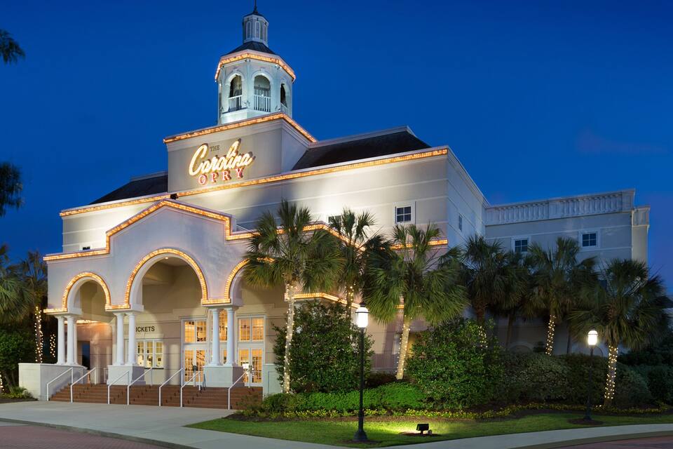 A theater with a marquee reading "The Color Purple" and a bell tower.