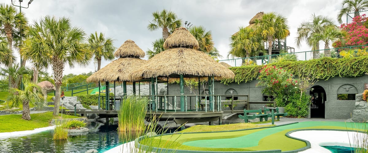 A tropical resort with thatched-roof huts, a swimming pool, and lush greenery.