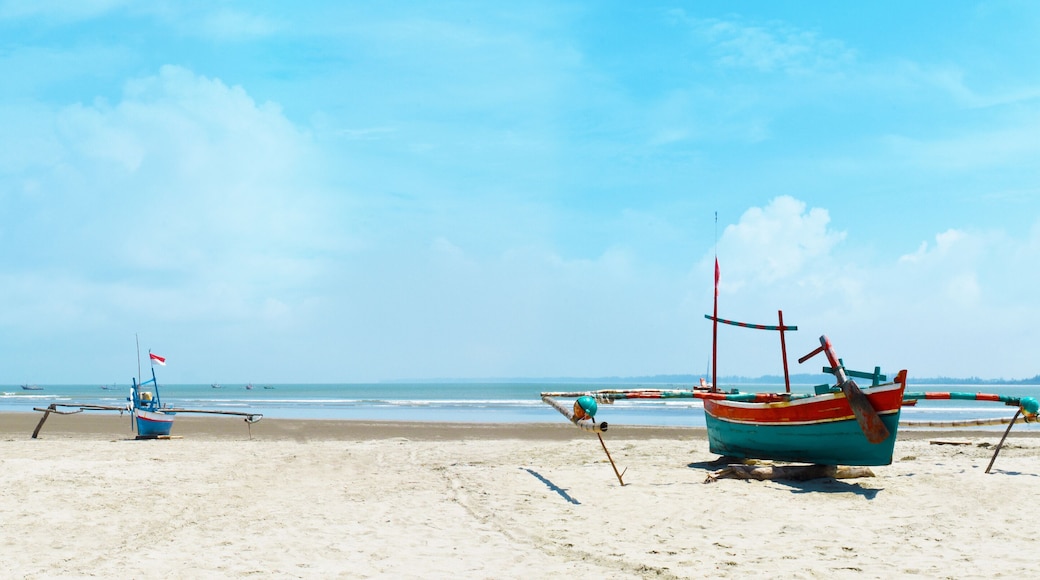 Panoramic beautiful tropical beach with wooden fishing boat and blue sky in the morning at Bengkulu beach Indonesia.