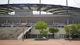 Indgangen til Seoul World Cup Stadion med trapper, træer og få parkerede biler.