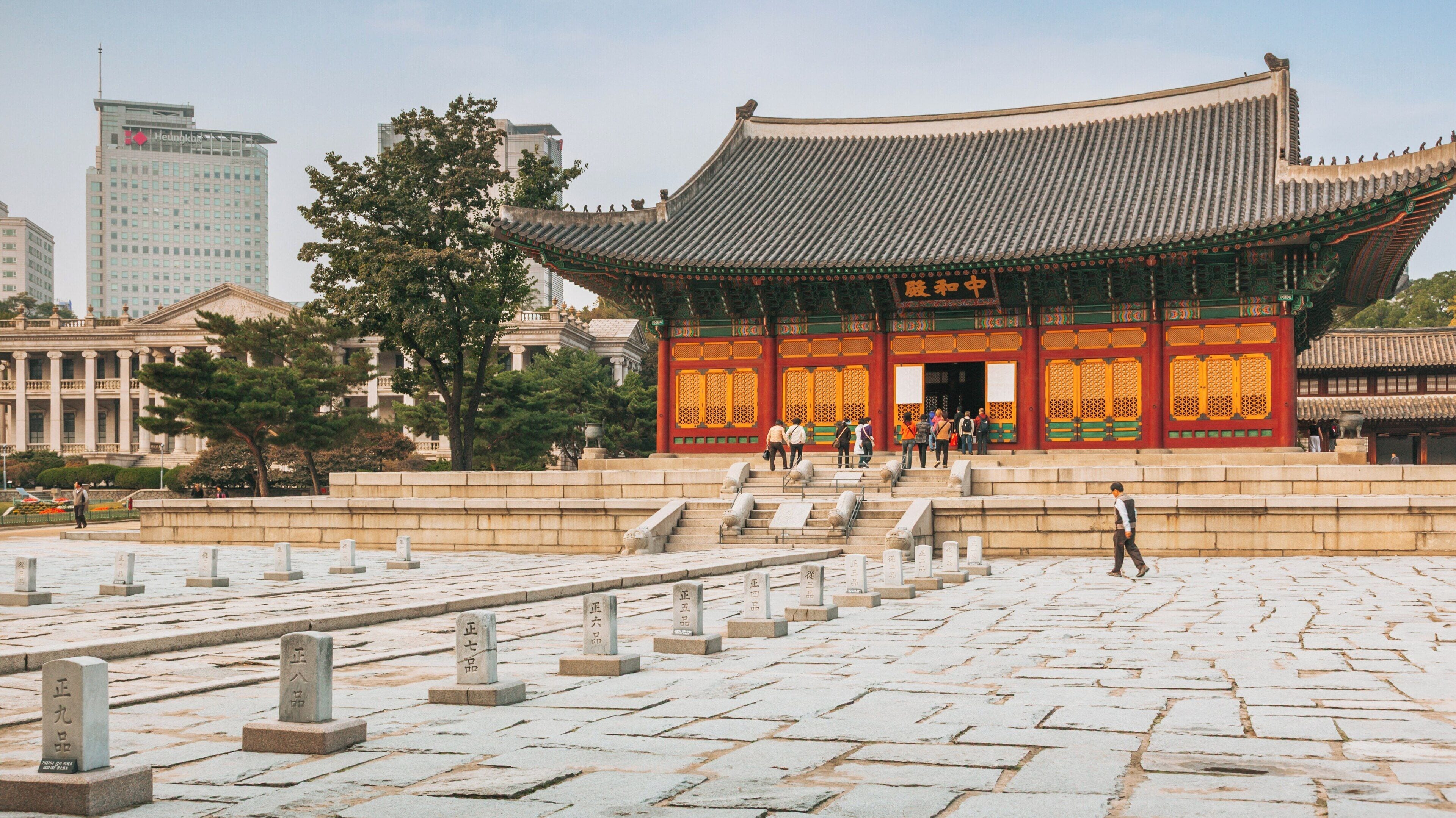 Visitors explore Deoksugung Palace in Jung-gu, Seoul, South Korea while surrounded by historical architecture and modern city skyline