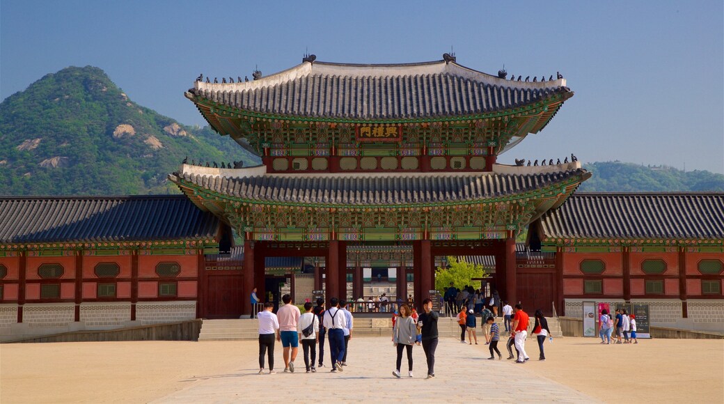 Gyeongbok Palace which includes a square or plaza and heritage architecture as well as a small group of people