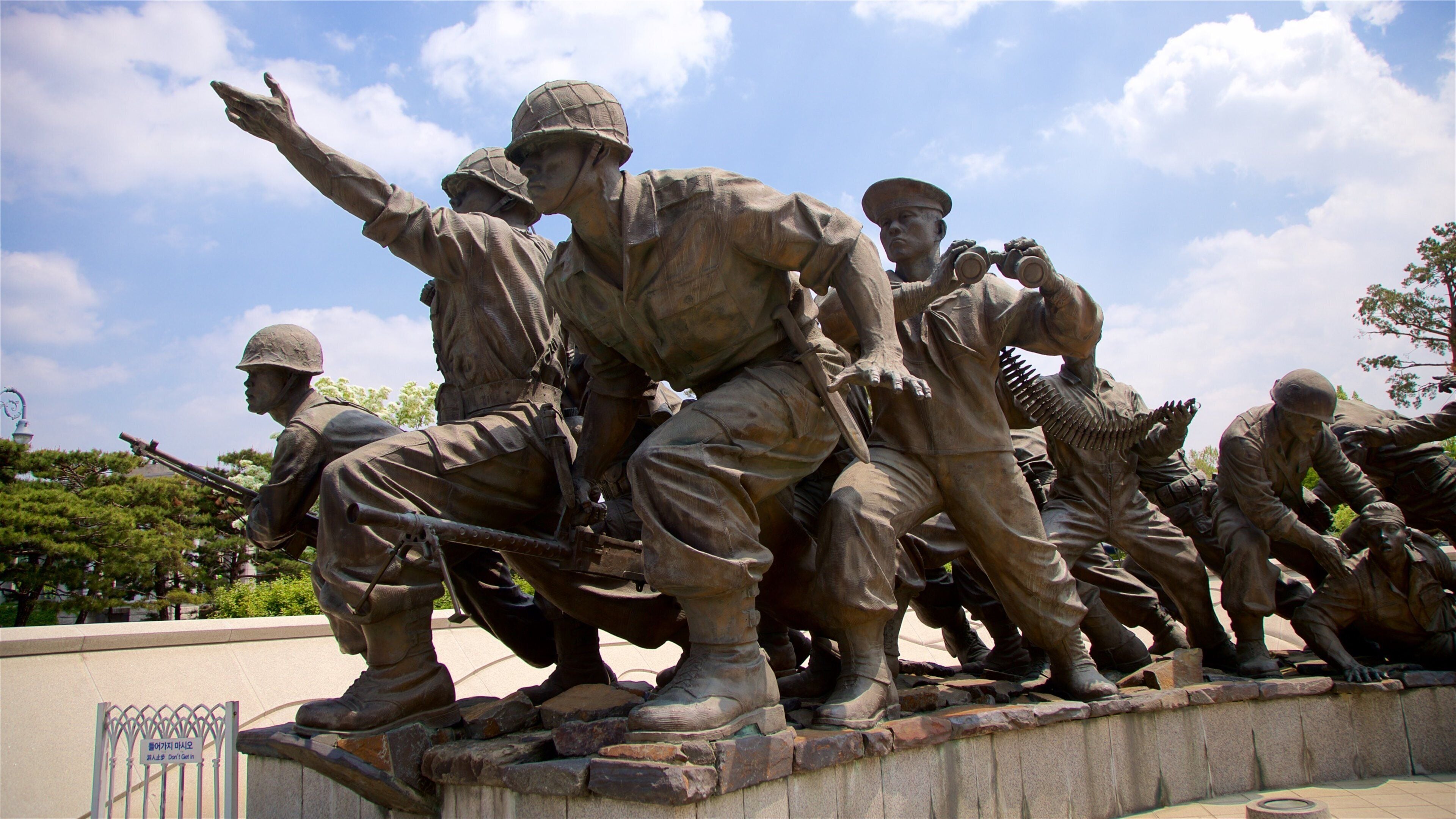 A bronze statue of soldiers in various poses, including one pointing upwards and another holding binoculars.