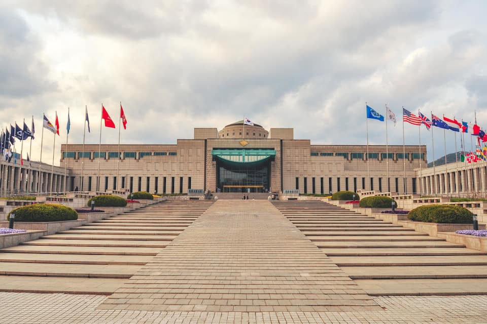 A large building with a central entrance and multiple flags on either side.