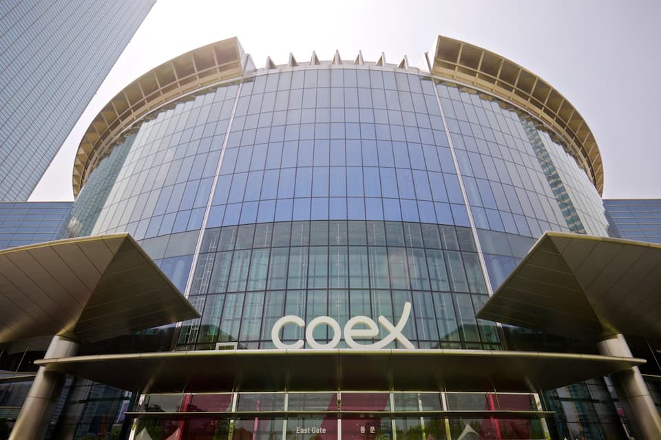 A modern glass building with the 'coex' logo.