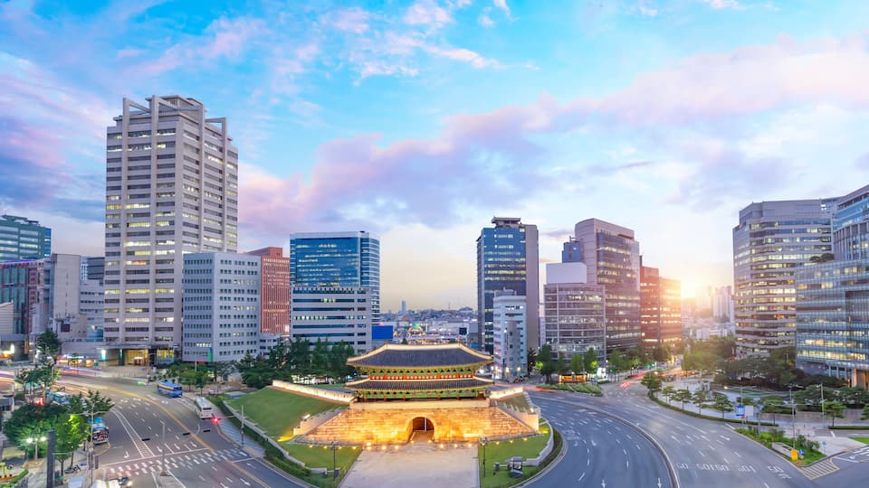 Paisagem urbana com edifícios modernos altos, um portão tradicional e um carrossel.