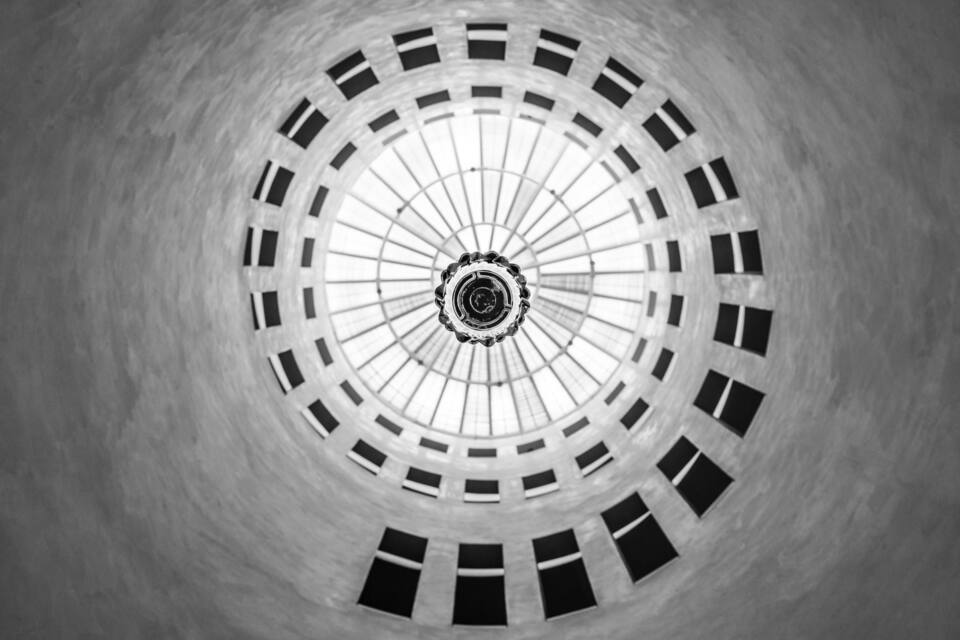 A spiral staircase leading up to a circular skylight.