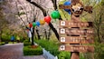 A wooden signpost with directional arrows and Korean text, surrounded by cherry blossoms and colorful lanterns.
