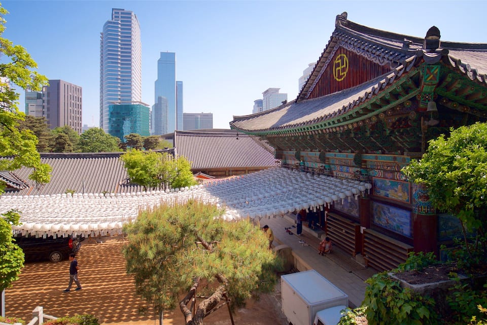 Un palais coréen traditionnel, avec son toit recouvert de tuiles, entouré de gratte-ciel modernes.