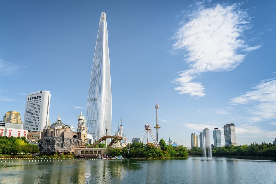 A modern skyscraper, a historic castle, and a body of water with a fountain.
