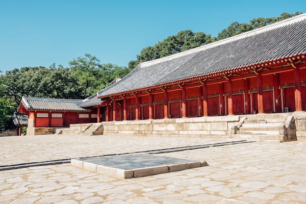 Un bùtiment traditionnel coréen, caractérisé par sa structure en bois peint en rouge et son toit recouvert de tuiles.