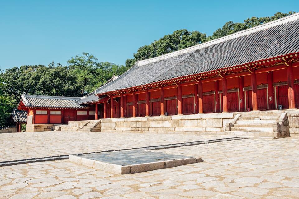 A traditional Korean building with red wooden structures and tiled roofs.