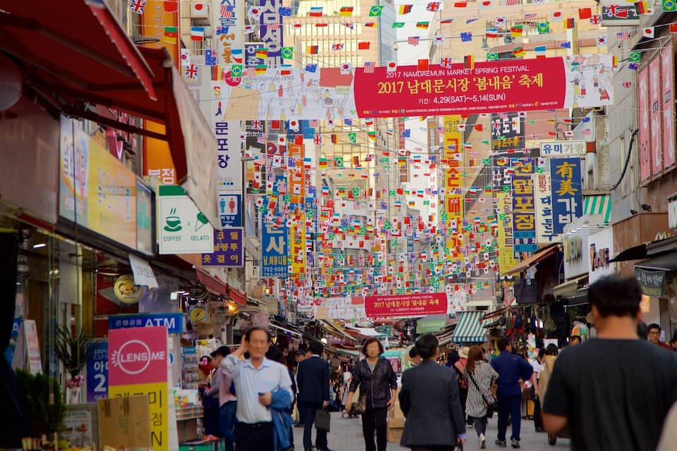A busy market street with numerous flags and signs in various languages.