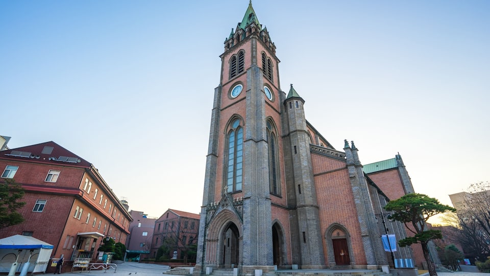 A historic church with a tall clock tower, a brick facade, and a clear sky.