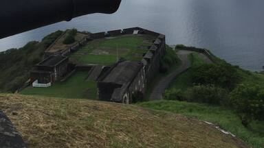 A coastal fortification with a large cannon overlooking the sea.